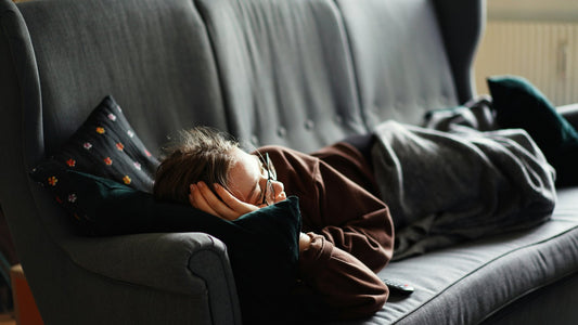 Man lying on the sofa with his head resting in his hand, deliberately slowing down after a demanding day