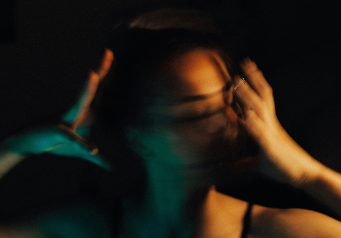 Blurred motion portrait of a woman pressing both hands to her head, expressing the overwhelm of ADHD burnout