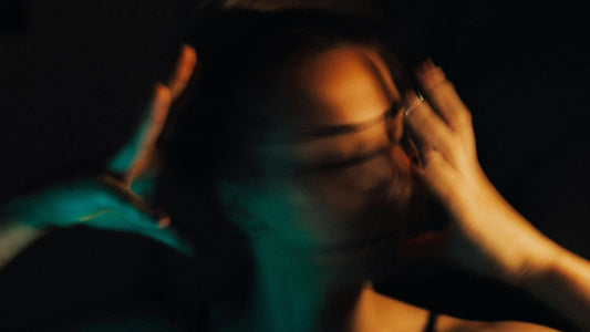Woman with hands pressed to her head in low light, conveying ADHD mental overwhelm and overload