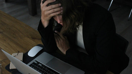 Exhausted person with head in hands at a desk, recognising early burnout symptoms