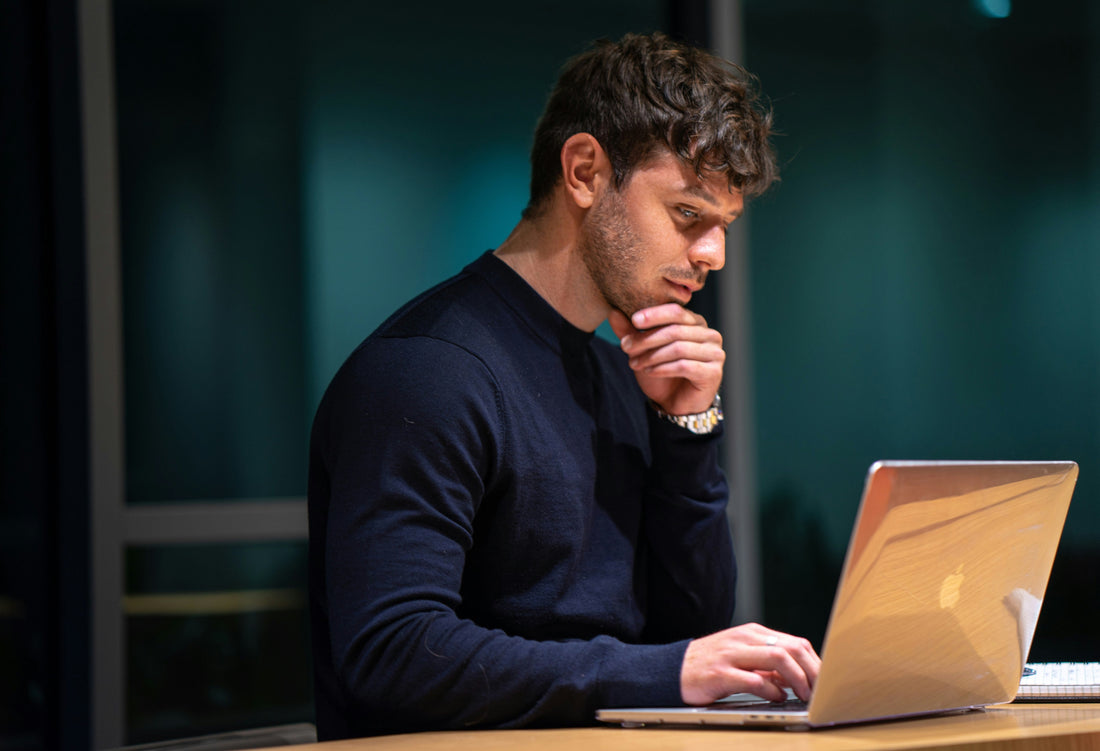 Man staring intently at a laptop in low light, losing track of time, ADHD time blindness