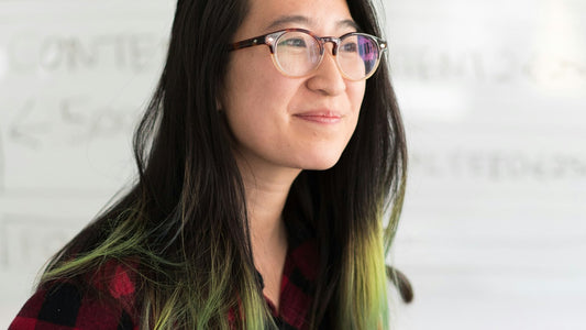 Woman planning her goals at a desk in front of a whiteboard, working out what to put on a vision board