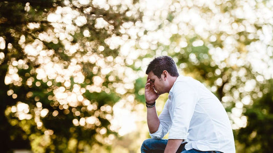 Man sitting alone outdoors with head in hand, experiencing creative burnout
