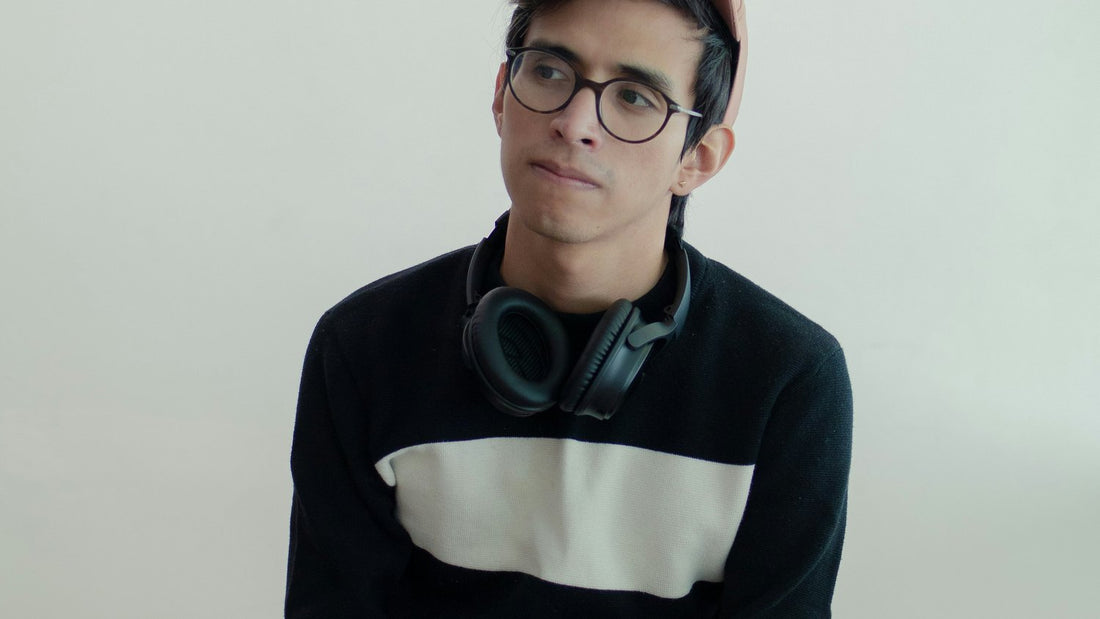 Young man with headphones resting around his neck, composed and present, learning to focus on yourself means stepping out of performance mode and back into presence