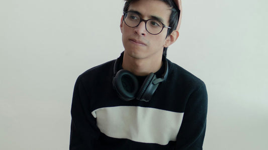 Young man with headphones resting around his neck, composed and present, learning to focus on yourself means stepping out of performance mode and back into presence