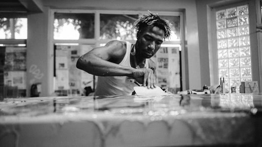 Man painting a large canvas in a bright studio, focused expression, black and white portrait of concentration