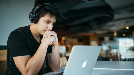 Man with headphones absorbed in laptop work at a café, in a state of deep focus