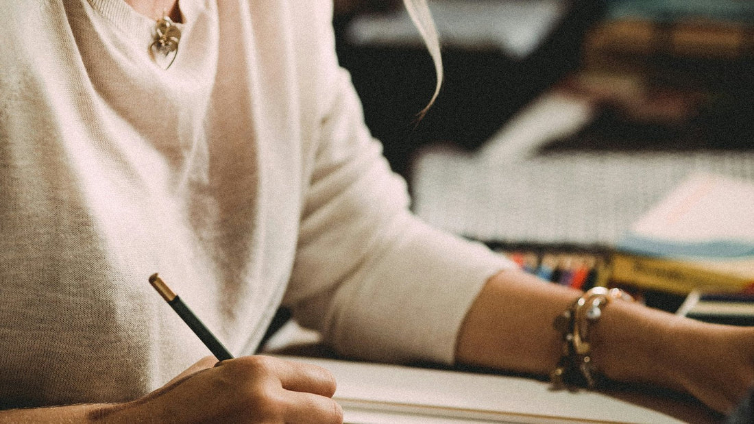 Person writing closely in a notebook in the evening, building a gratitude routine before bed