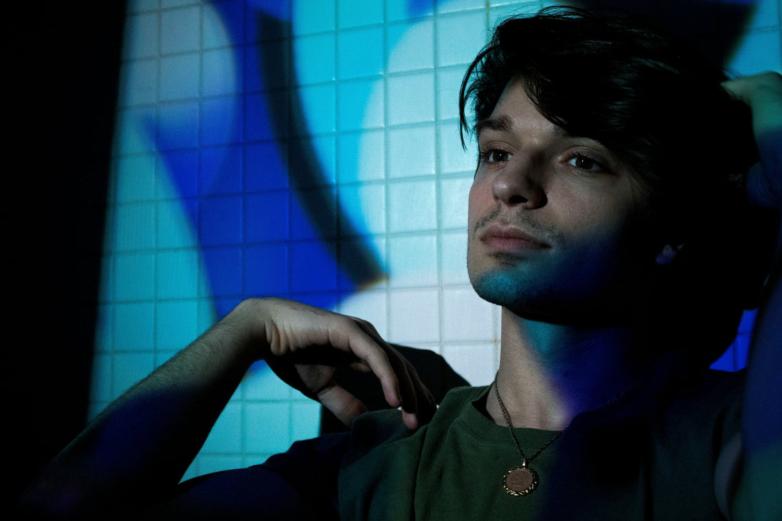 Young man gazing distantly against a blue wall with an unfocused expression, representing the clouded mental state of ADHD brain fog