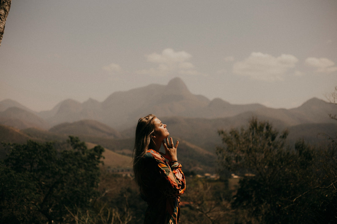 Woman standing on a hilltop eyes closed, face raised to the sky, representing ADHD burnout recovery and reset