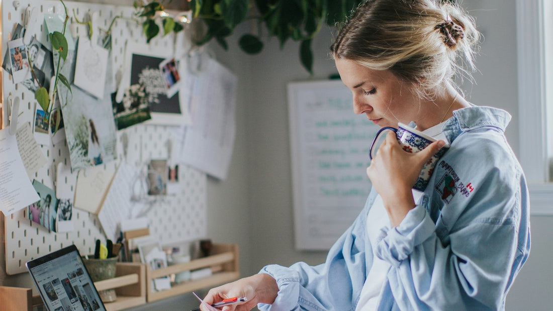 Woman at a desk reviewing a vision board and colour swatches — planning and organising with a planner