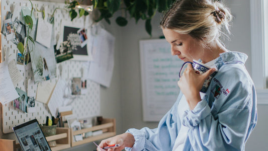 Woman at a desk reviewing a vision board and colour swatches — planning and organising with a planner