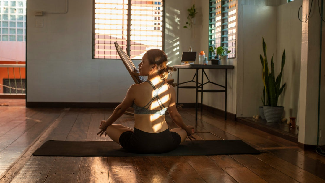 Woman meditating on a mat in a sunlit room, grounding her body to get out of her head