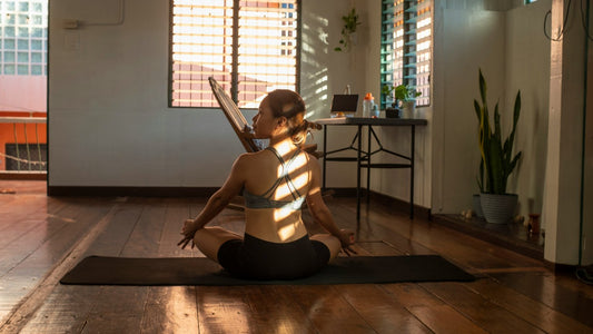 Woman meditating on a mat in a sunlit room, grounding her body to get out of her head