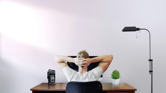 Man sitting at desk with hands behind head, reflecting and reviewing his progress