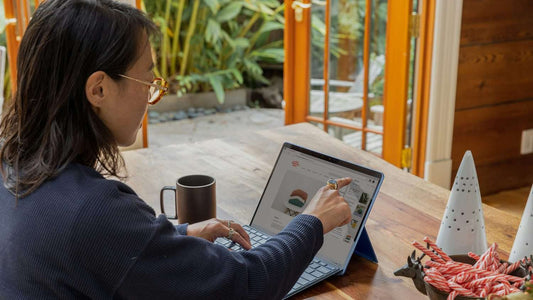 Woman working at a wooden desk with tablet in warm morning light, intentional and focused