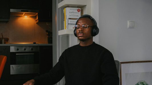 Man with headphones sitting still with eyes closed at home, practising nervous system regulation