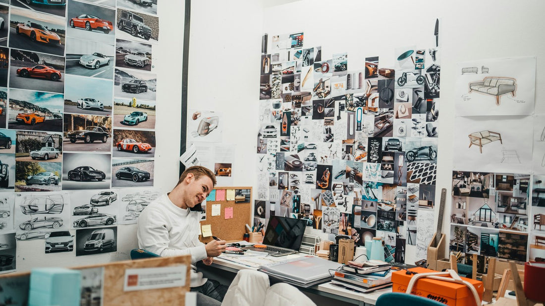 Man sitting at a desk surrounded by a mood board, focused while planning his direction for the year