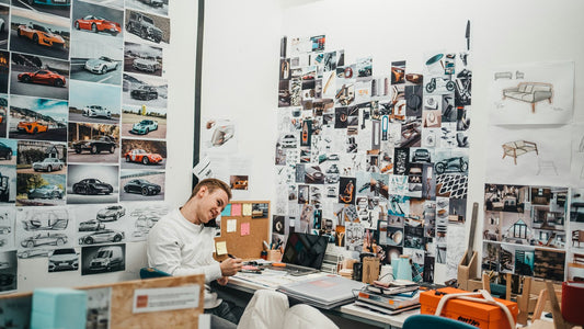 Man sitting at a desk surrounded by a mood board, focused while planning his direction for the year