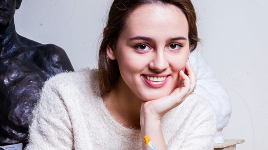 Woman artist smiling with paintbrush in a creative studio — the joyful, aspirational energy a vision board is designed to activate