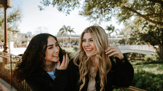 Two women laughing and talking outdoors, sharing a relaxed and joyful moment, free from the pressure of perfectionism