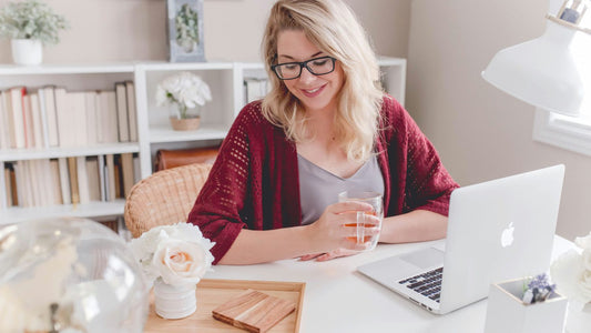 Woman working at a bright home desk with a laptop, typing notes, benefits of handwriting vs typing
