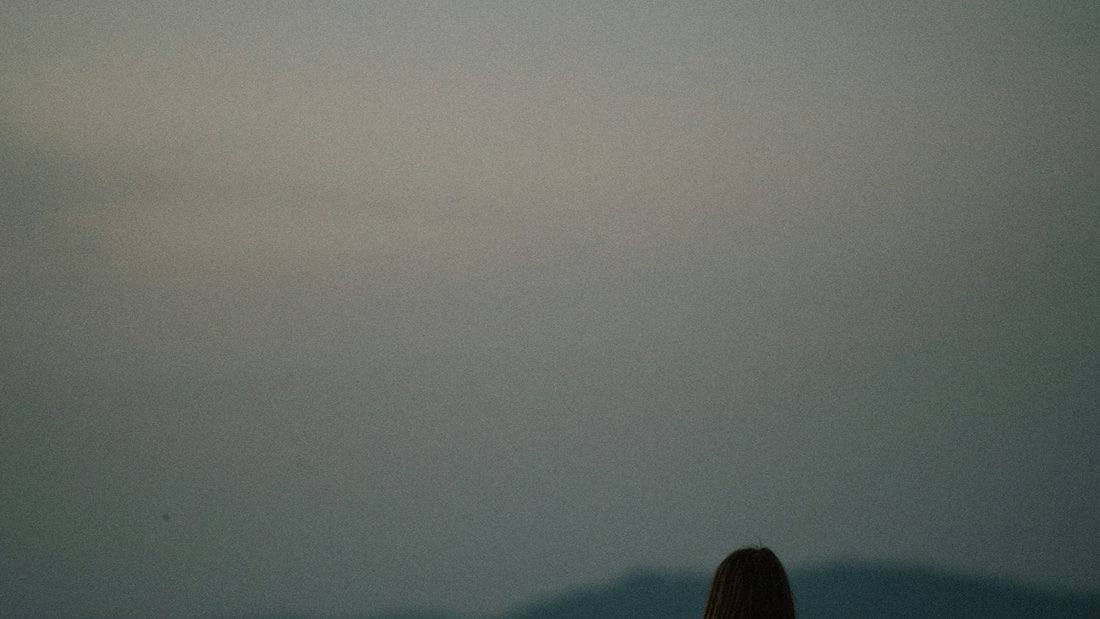 Person at a laptop appearing stressed and overwhelmed at work, papers and coffee in front of them