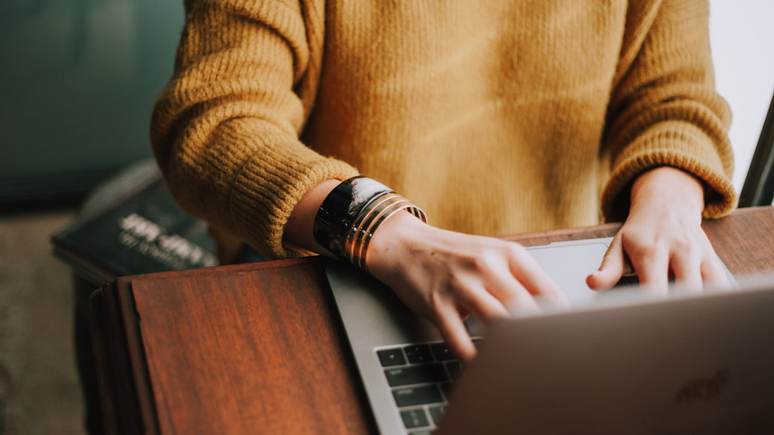 Woman working calmly at a laptop in a warm room, composed and capable outwardly, the quiet face of high-functioning anxiety