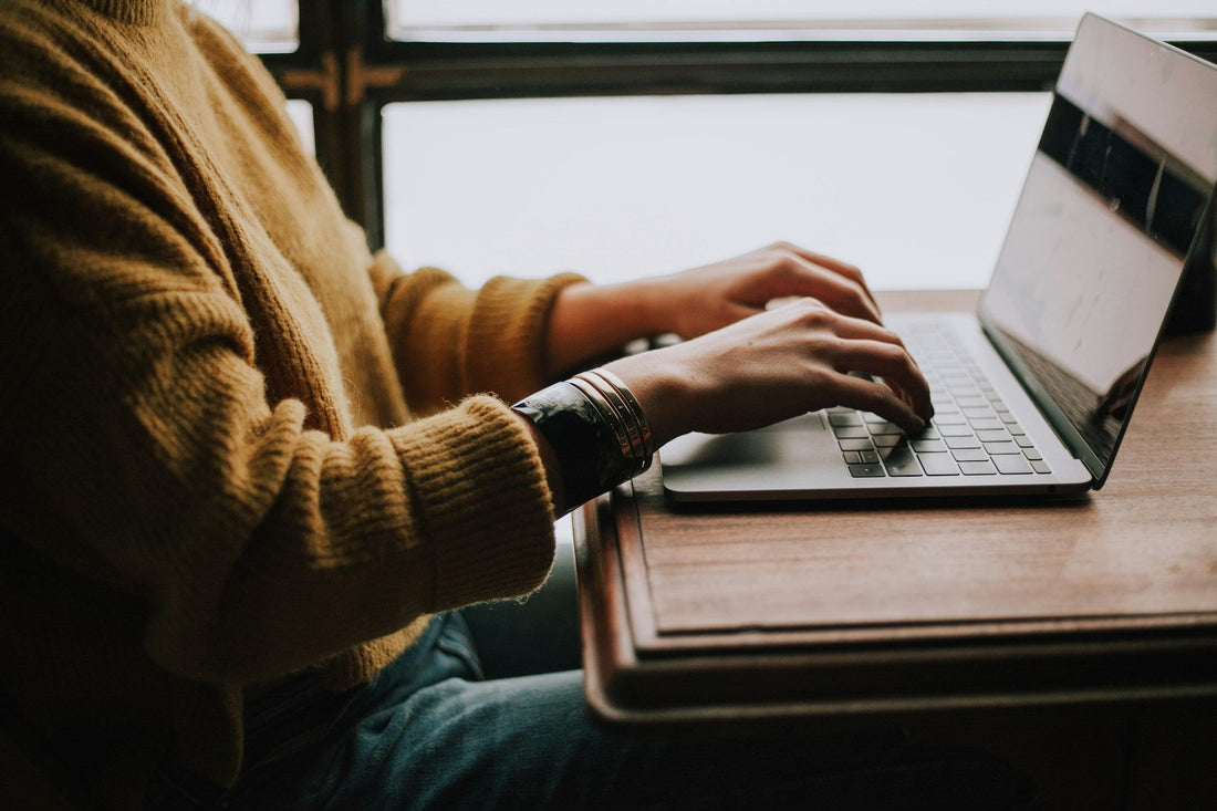Hands typing swiftly at a laptop, handling a quick two-minute task before it accumulates on the list