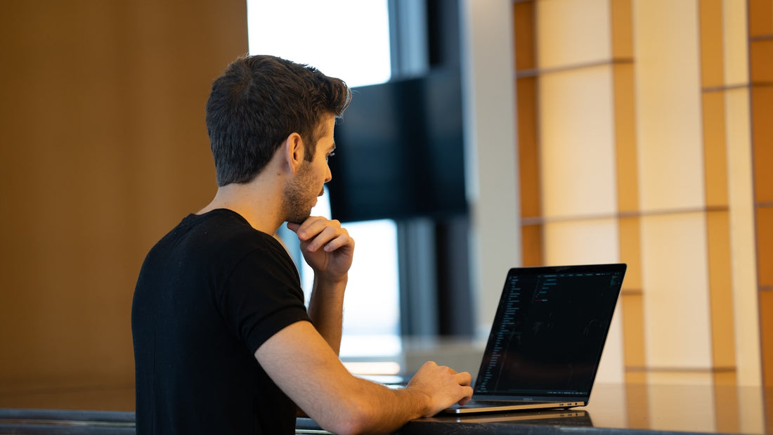 Man working late on a laptop in a dim room, the screen holding his full attention