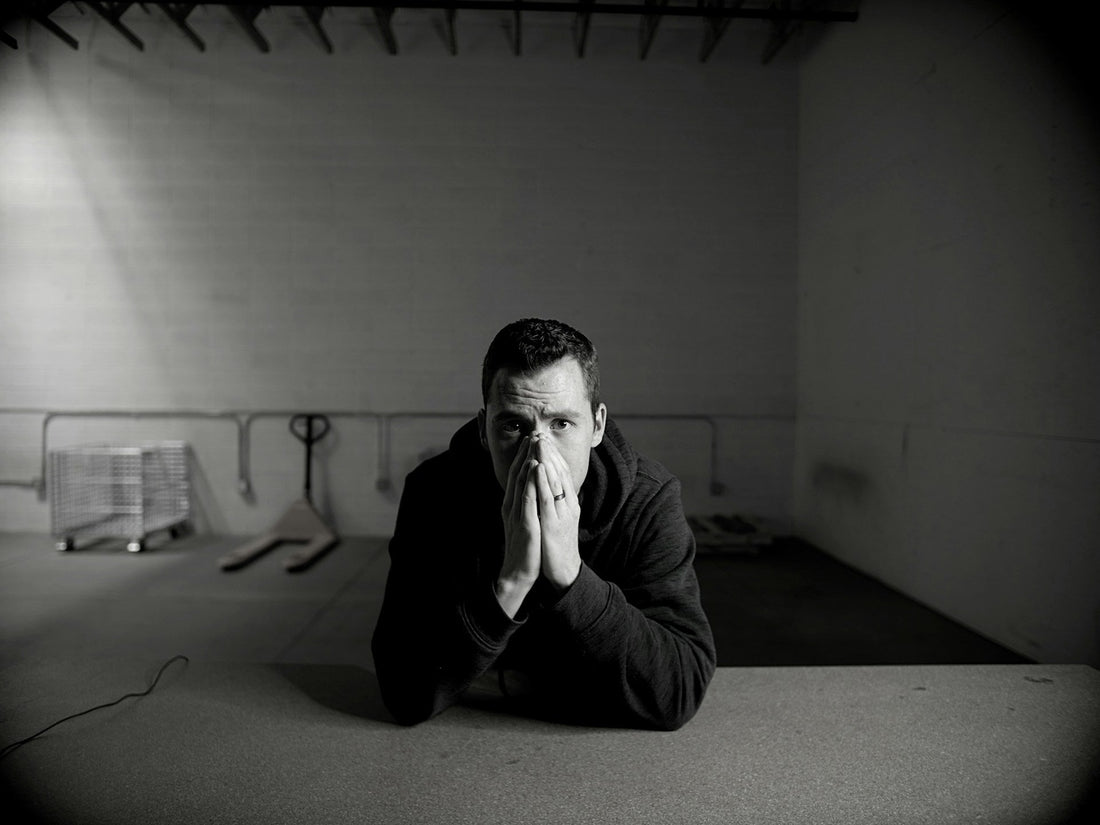 Man holding both hands over his nose and mouth at a desk, tense and stressed before using the physiological sigh