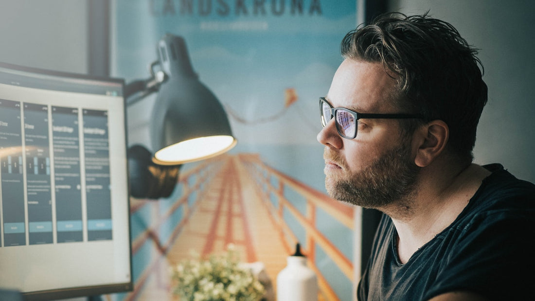Man in glasses absorbed at his computer in a home office, locked into deep focus on a single task