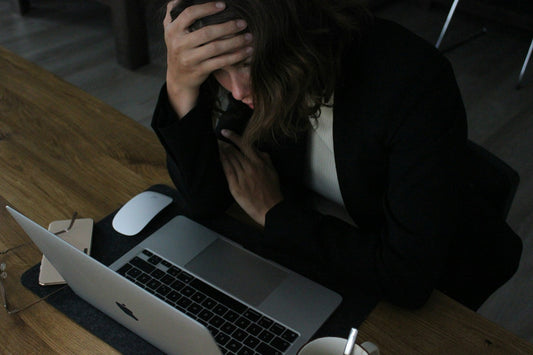 Person sitting at a desk looking depleted and overwhelmed, a face of toxic productivity