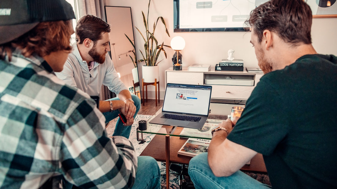 Three colleagues gathered around a laptop deciding which of the team's tasks to prioritise first
