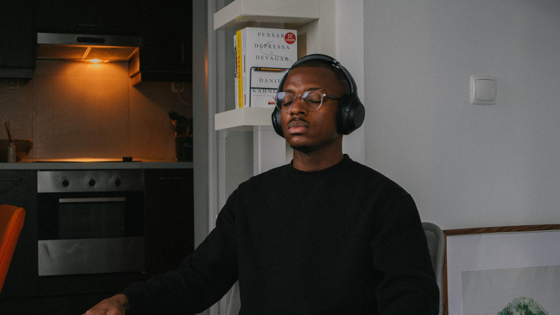 Man meditating with eyes closed wearing headphones in his kitchen at home