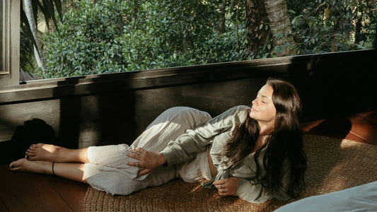 Woman lying cosily on the floor by a window in low winter light, low energy in the afternoon