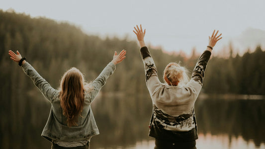 Person standing with arms raised facing a forest lake, a moment of release and clarity, daily journaling habit