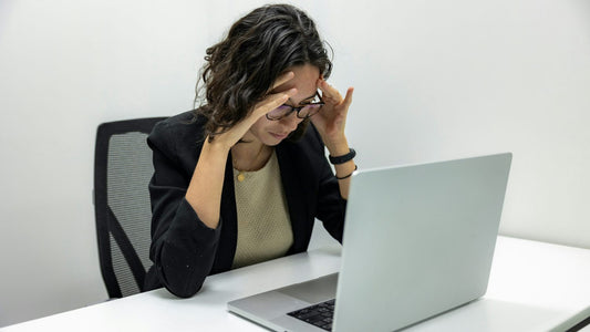 Stressed woman with head in hands at a laptop, struggling to focus, how to improve self-control