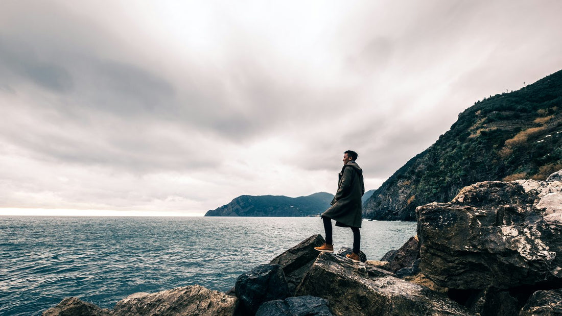 Man standing alone on coastal rocks looking out to sea, reflecting on what self-actualisation actually means