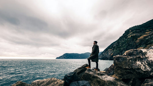 Man standing alone on coastal rocks looking out to sea, reflecting on what self-actualisation actually means