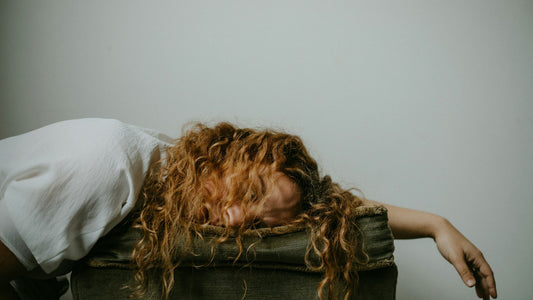 Woman slumped face-down over the arm of a chair, exhausted after another cycle of self-sabotage