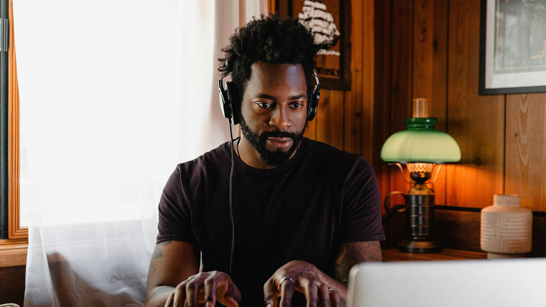 Focused man with headphones playing keyboard at home, absorbed in his own capability