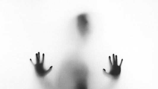 Person pressing hands against frosted glass, feeling trapped by overstimulation before a dopamine detox