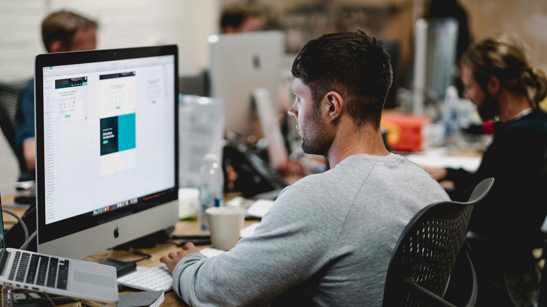 A man concentrating at a desktop computer in an open-plan office, the steady focus executive function makes possible