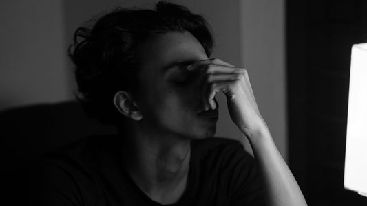 Woman resting her head in her hand at a dim desk beside a notebook and alarm clock, unable to hold herself accountable
