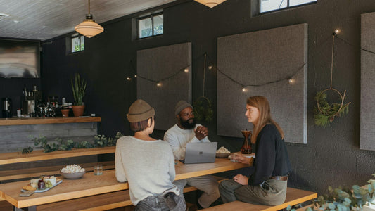 Three people setting SMART goals together with a laptop in a calm café, planning the year ahead