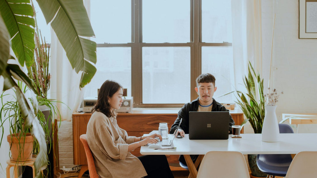 Two people working independently side by side at a table — body doubling technique to improve ADHD focus