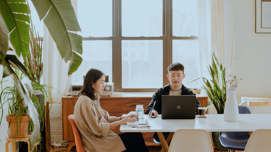 Two people working independently side by side at a table — body doubling technique to improve ADHD focus