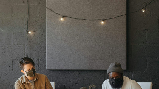 Woman writing in a small notebook at a wooden desk with her phone face-down beside her