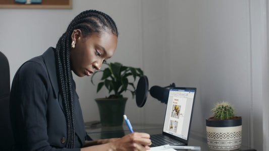 Woman writing in a self care journal at a home desk, calm and reflective in soft daylight